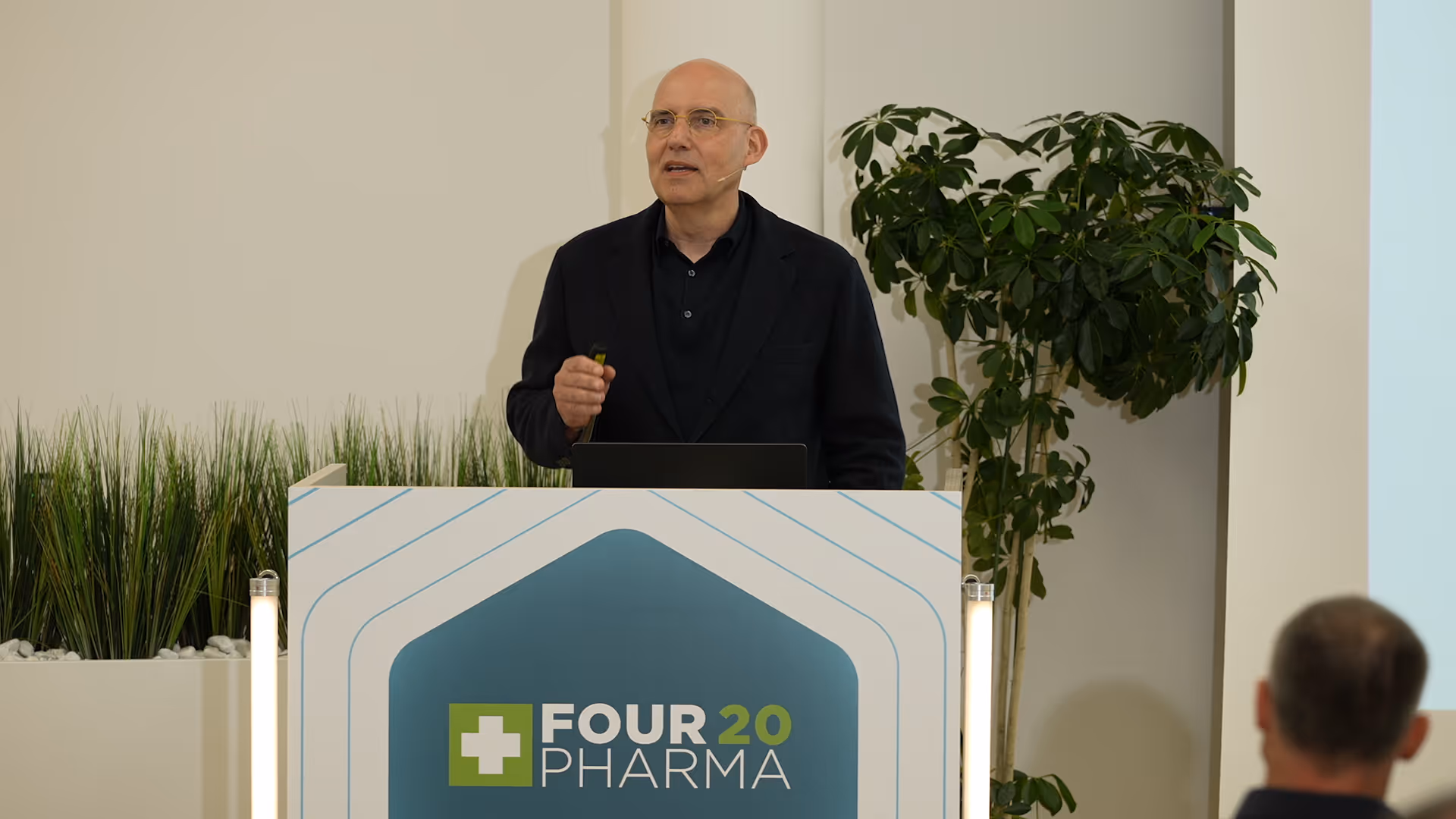 Mann mit Brille spricht bei einer Four20 Pharma-Veranstaltung an einem Rednerpult.