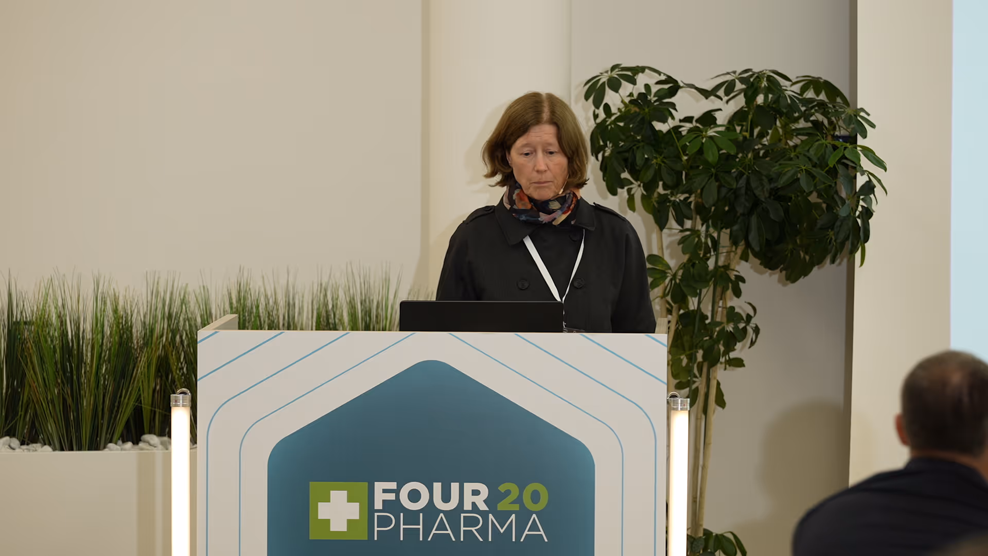Frau steht am Rednerpult mit Four 20 Pharma-Logo und spricht vor Publikum.