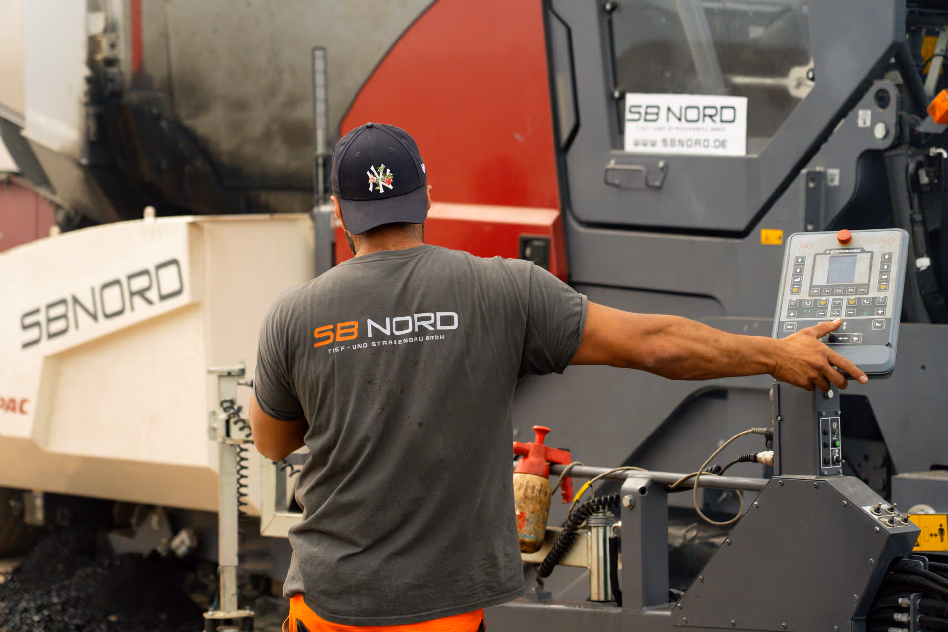 Mann bedient Steuerungsgerät an einer großen Baumaschine mit SB NORD-Logo.