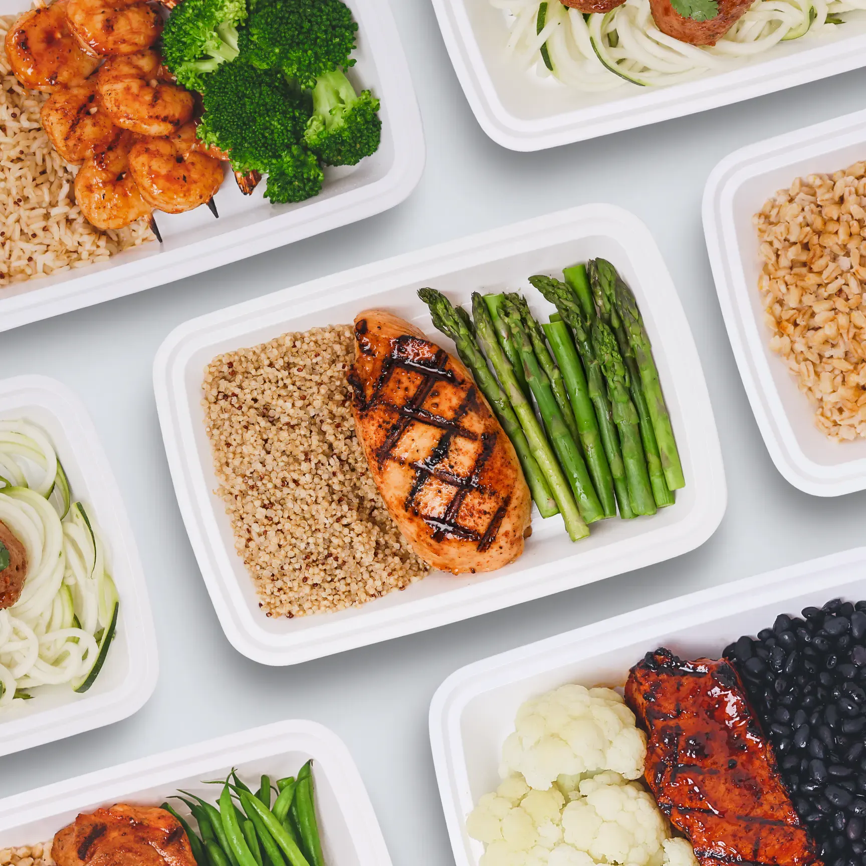 A variety of foods are displayed in a row of containers.