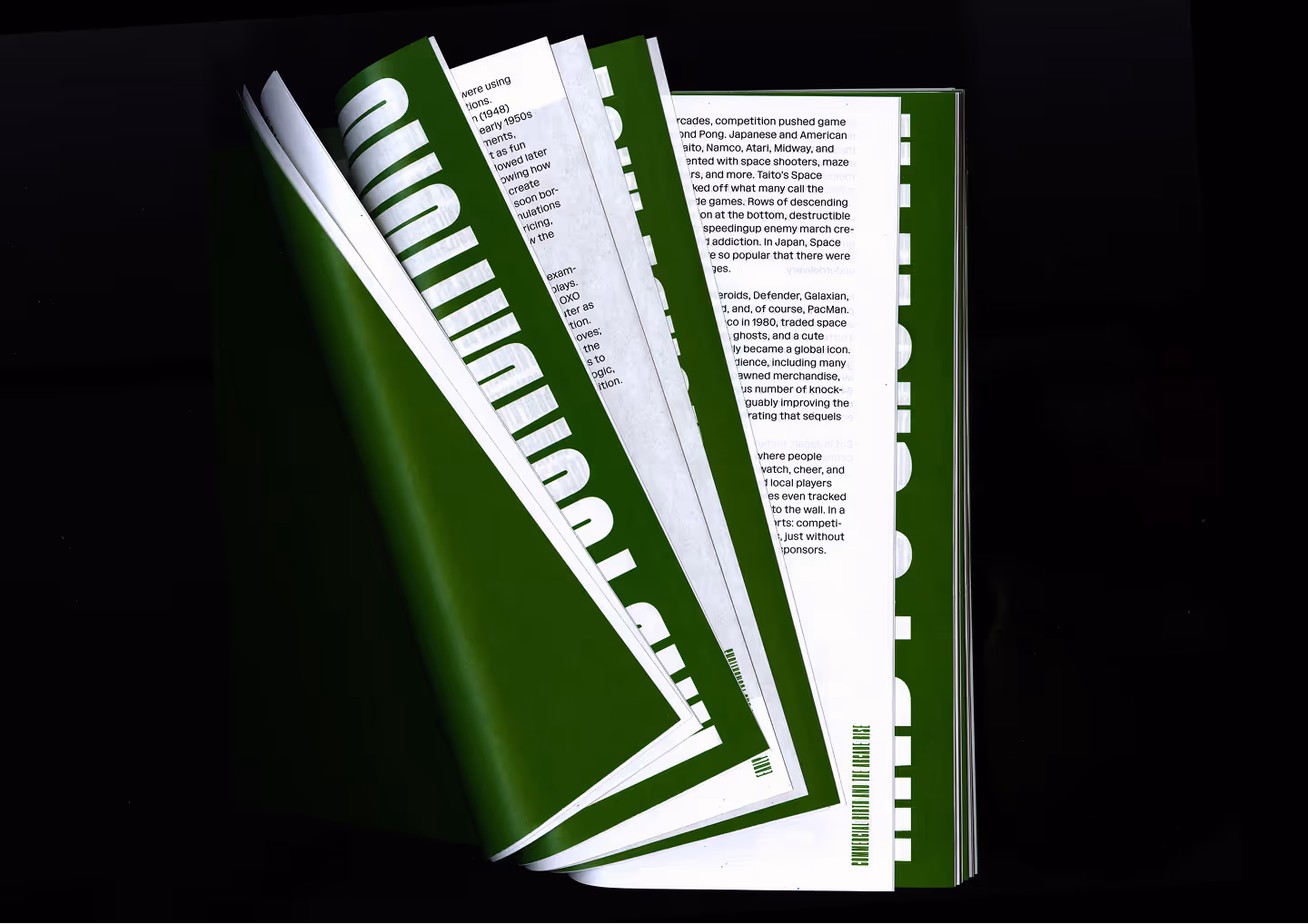 Open book with green and white pages featuring text and bold graphics, photographed on black background.