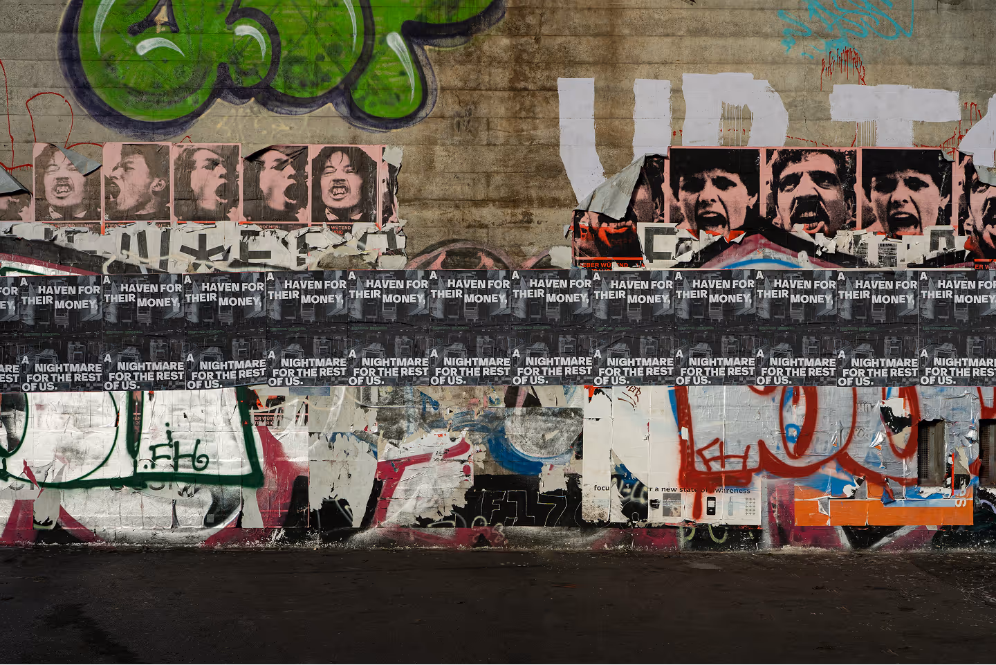 Posters lined up next to each other on a wall with graffiti.