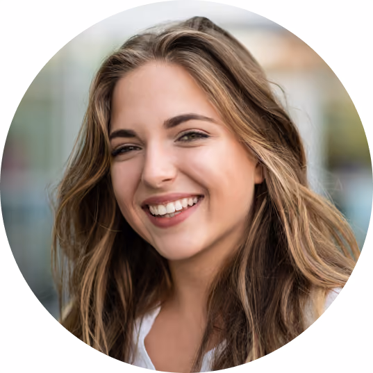 Smiling young woman with long, wavy blond hair and natural makeup against blurred background.