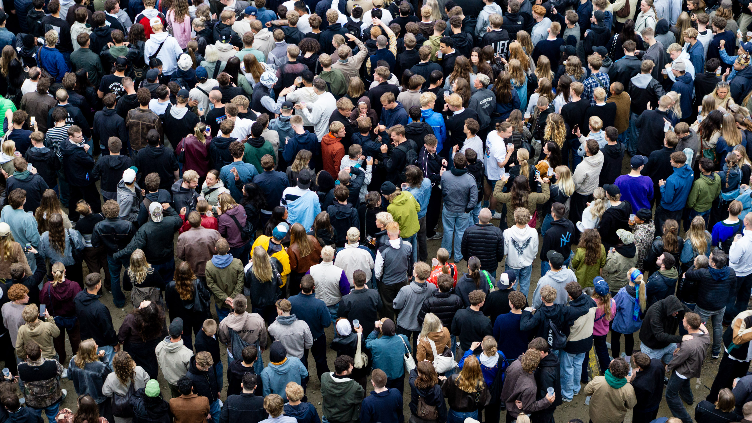Large crowd of people standing closely together at an outdoor event.