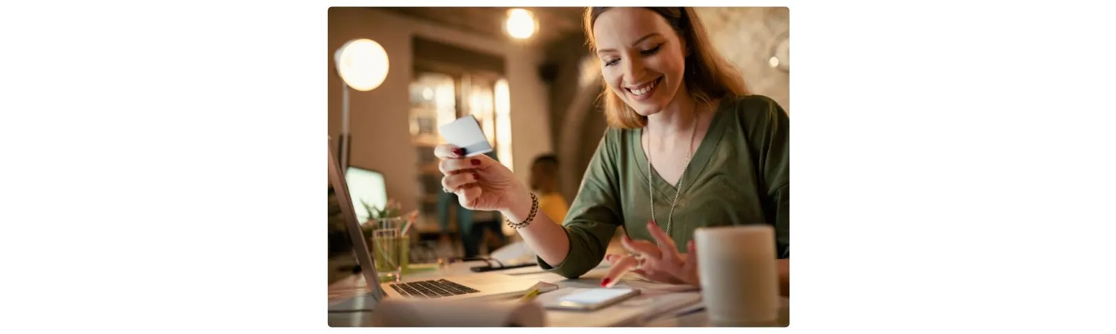 Cliente tenant sa carte bancaire devant un ordinateur portable pour payer en ligne