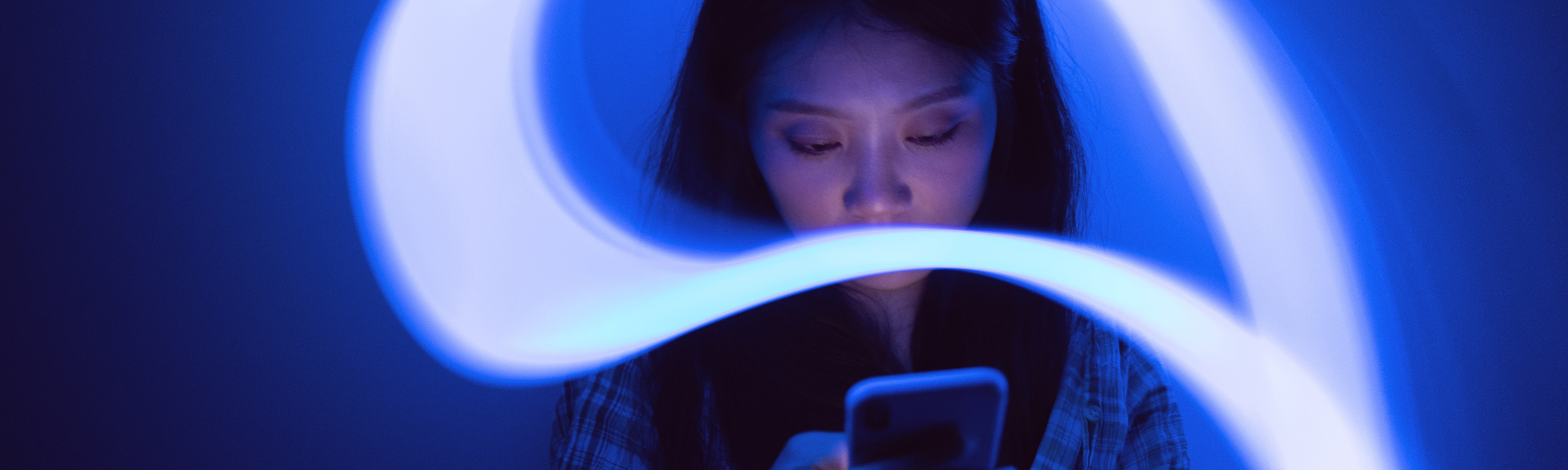 Person using a smartphone, surrounded by blue light trails illustrating a continuous digital journey.