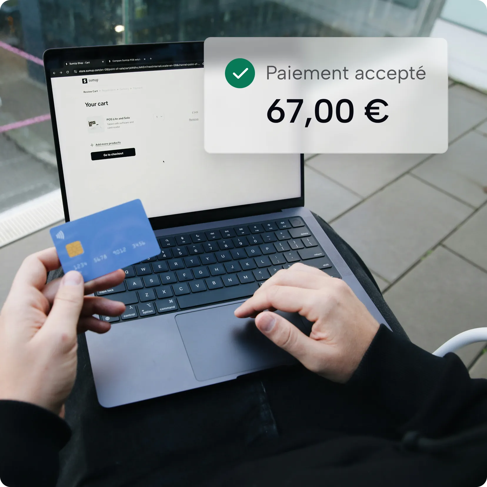 Person tenant une carte bleue devant un ordinateur portable avec message de paiement accepté de 67 €.