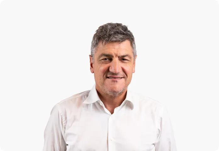Portrait d'un homme souriant portant une chemise blanche sur fond blanc.
