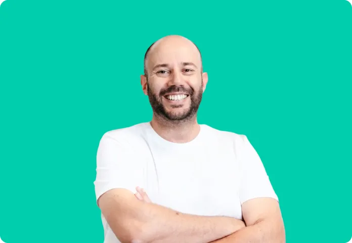 Homme souriant, torse croisé, portant un t-shirt blanc devant un fond vert.