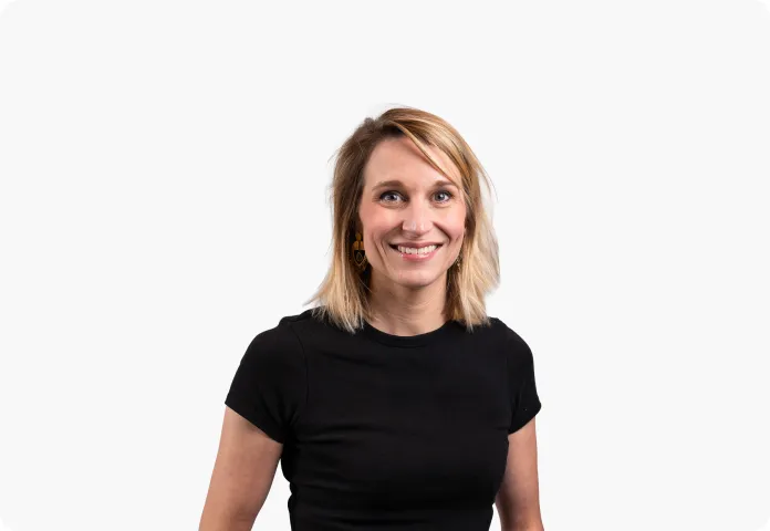 Femme souriante aux cheveux blonds portant un t-shirt noir sur fond blanc.