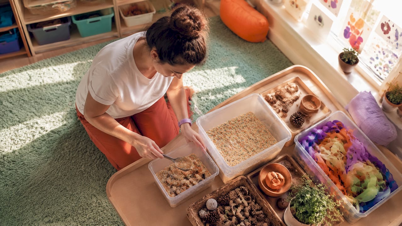 Educator arranging sensory play materials in sensory room