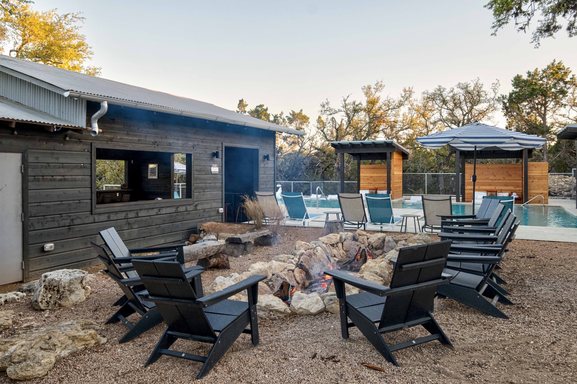Fire pits and Adirondack chairs in the social area at Lucky Arrow Springs at dusk