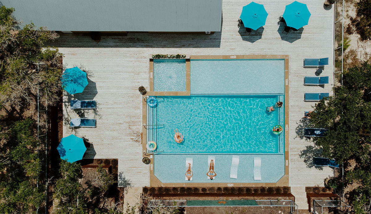 The heated pool at Lucky Arrow Springs from above, loungers and umbrellas around the deck
