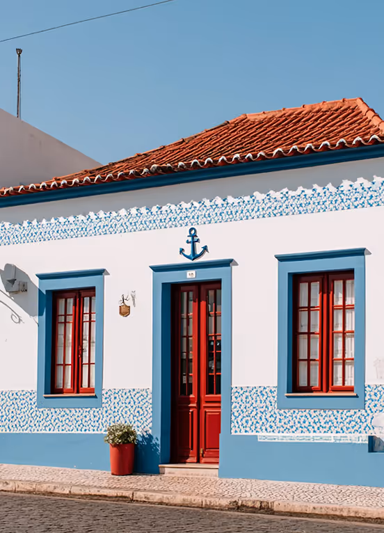 White house with blue trim, red doors and windows, red tile roof, and an anchor decoration above the door.