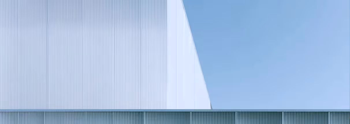 Minimalist modern building facade with vertical lines under a clear blue sky.