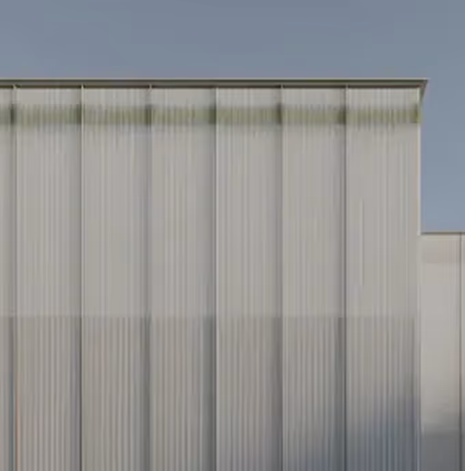 Modern building facade with large vertical translucent panels under a clear sky.
