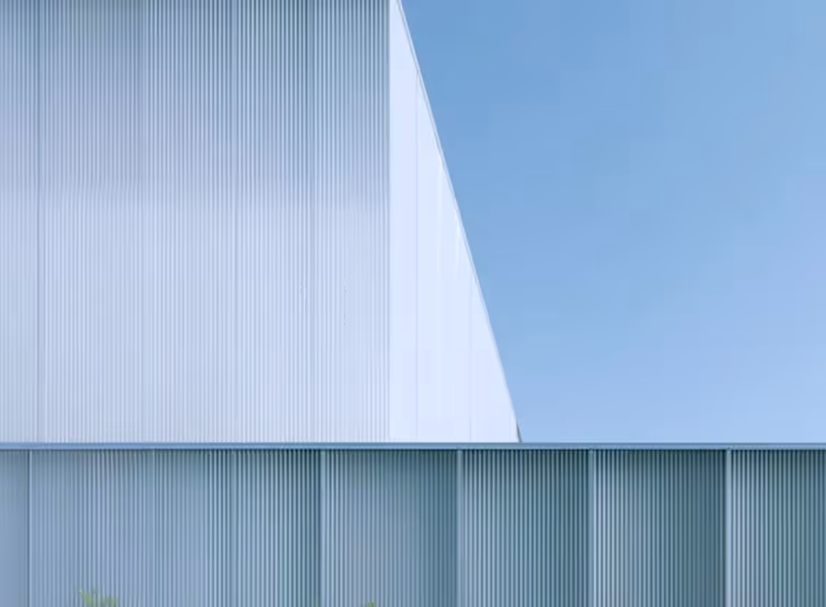 Modern building facade with vertical lines against a clear blue sky.