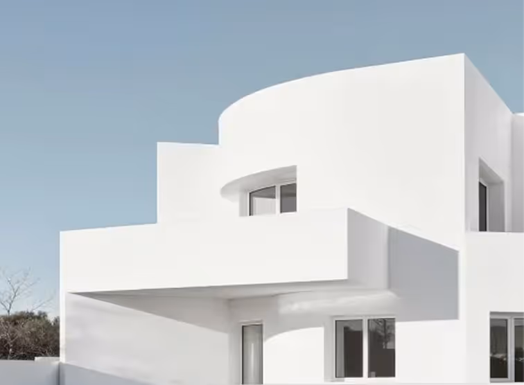 Modern white building with curved and rectangular architectural elements under a clear sky.