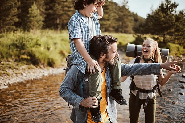 The same family hiking in the "spark" image on the homepage are seen here again. The father points to something out on the horizon as the mother looks at her son discovering something new and wonderous out among the trees.