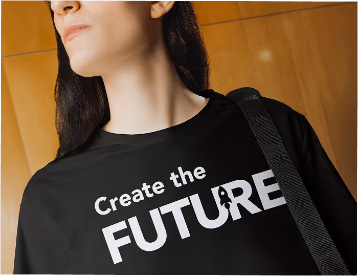 A person wearing a black t-shirt printed with "Create the FUTURE" in white type, a bag strap across one shoulder.