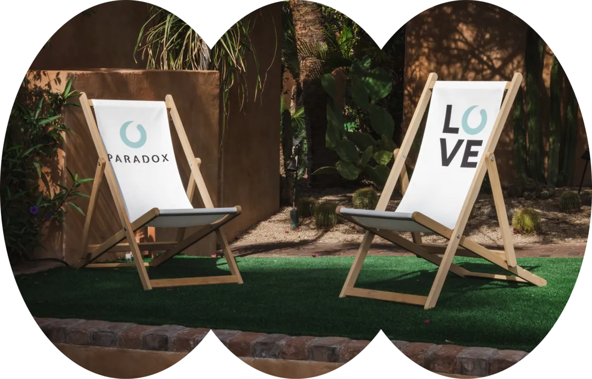 Two wooden deck chairs on artificial grass, one says PARADOX, the other says LOVE outdoors.
