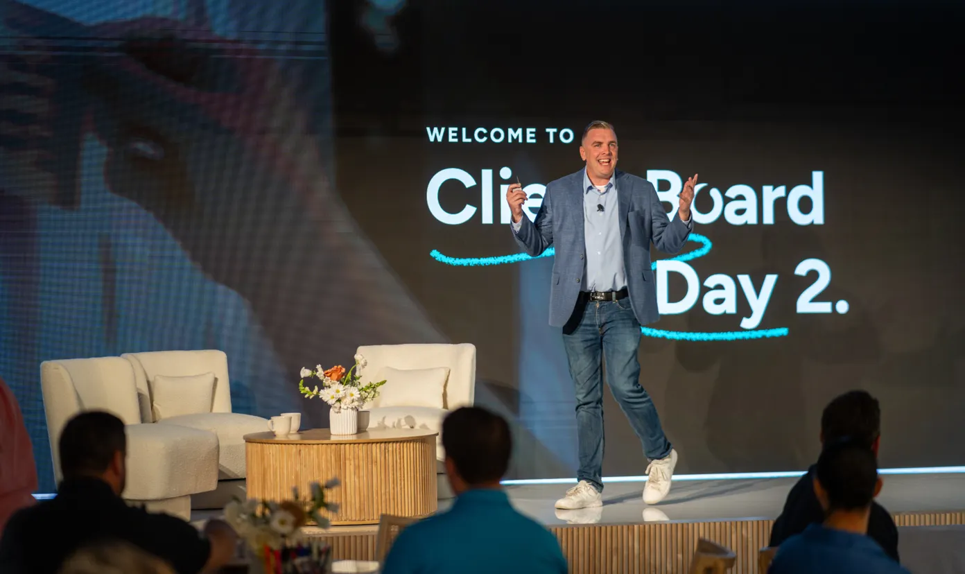 Man in blue blazer and jeans speaking on stage during a Clipboard Day 2 event.