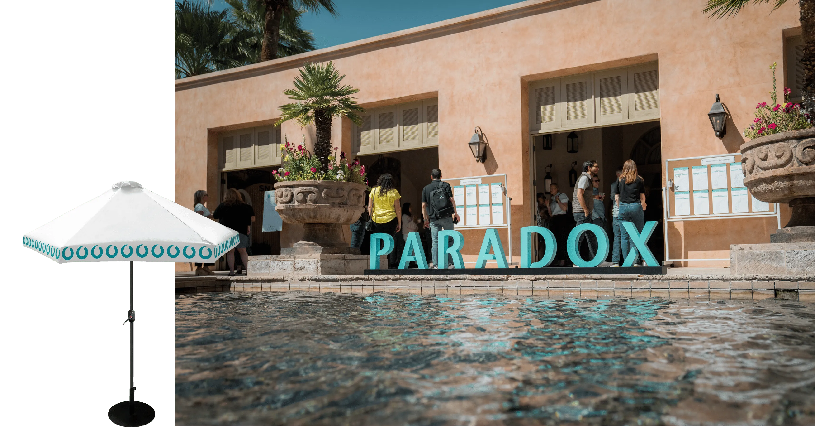 People near large blue letters spelling PARADOX by a stone planter and pool outside a stucco building.