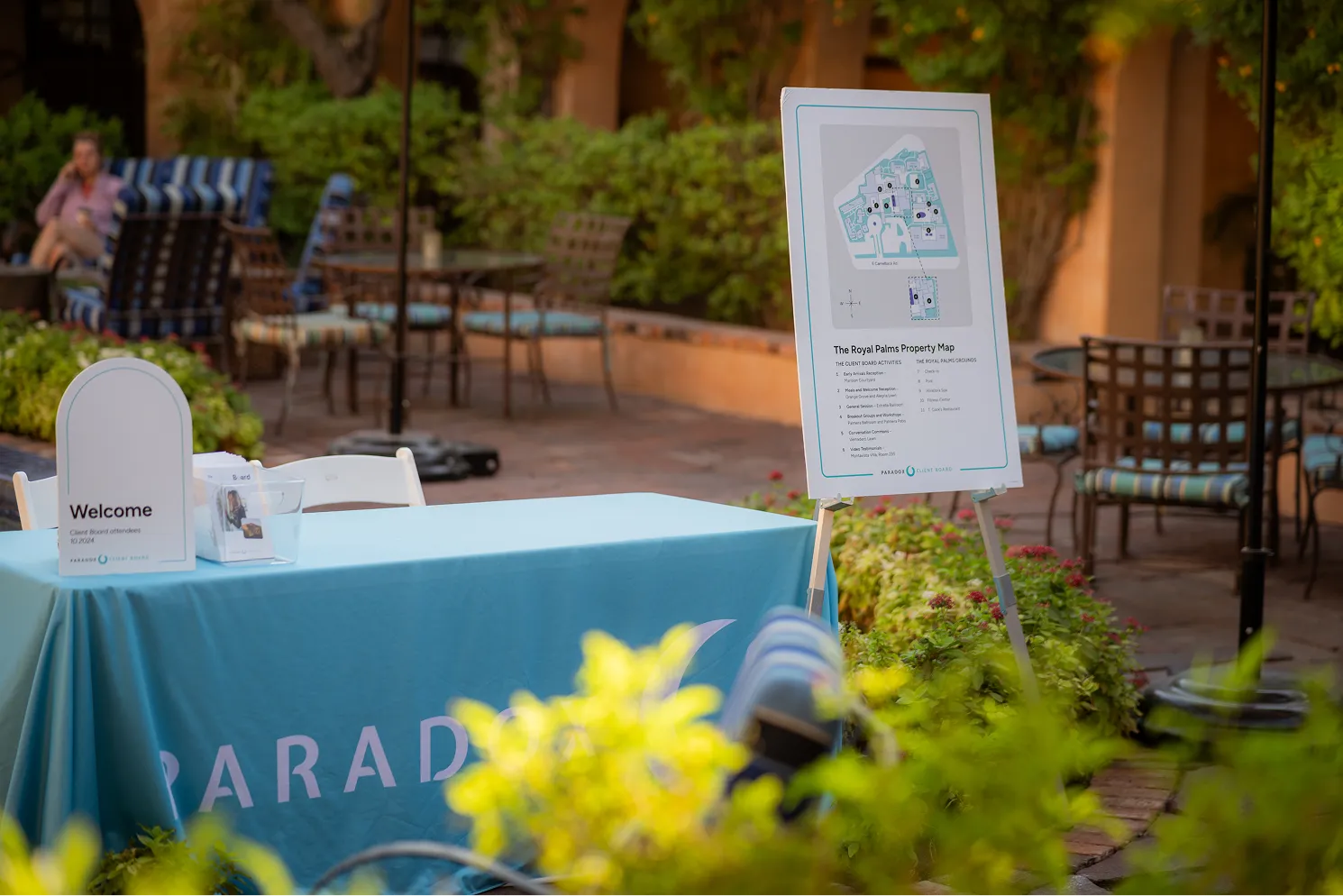Outdoor welcome table with blue cover and property map sign for Royal Palms at event venue.