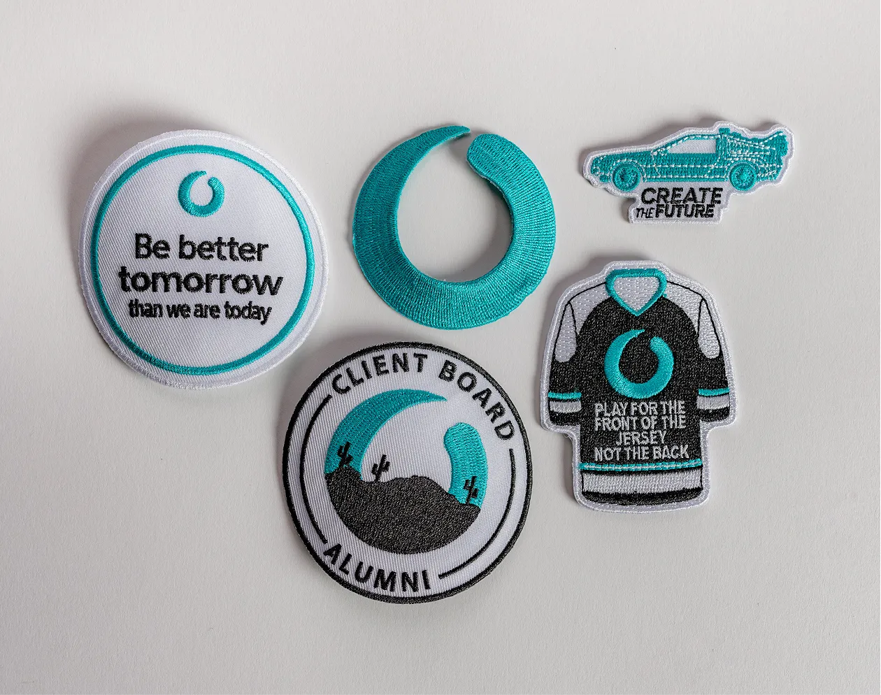 Five embroidered patches including a circle with text, a crescent, a car, a jersey, and a desert scene.