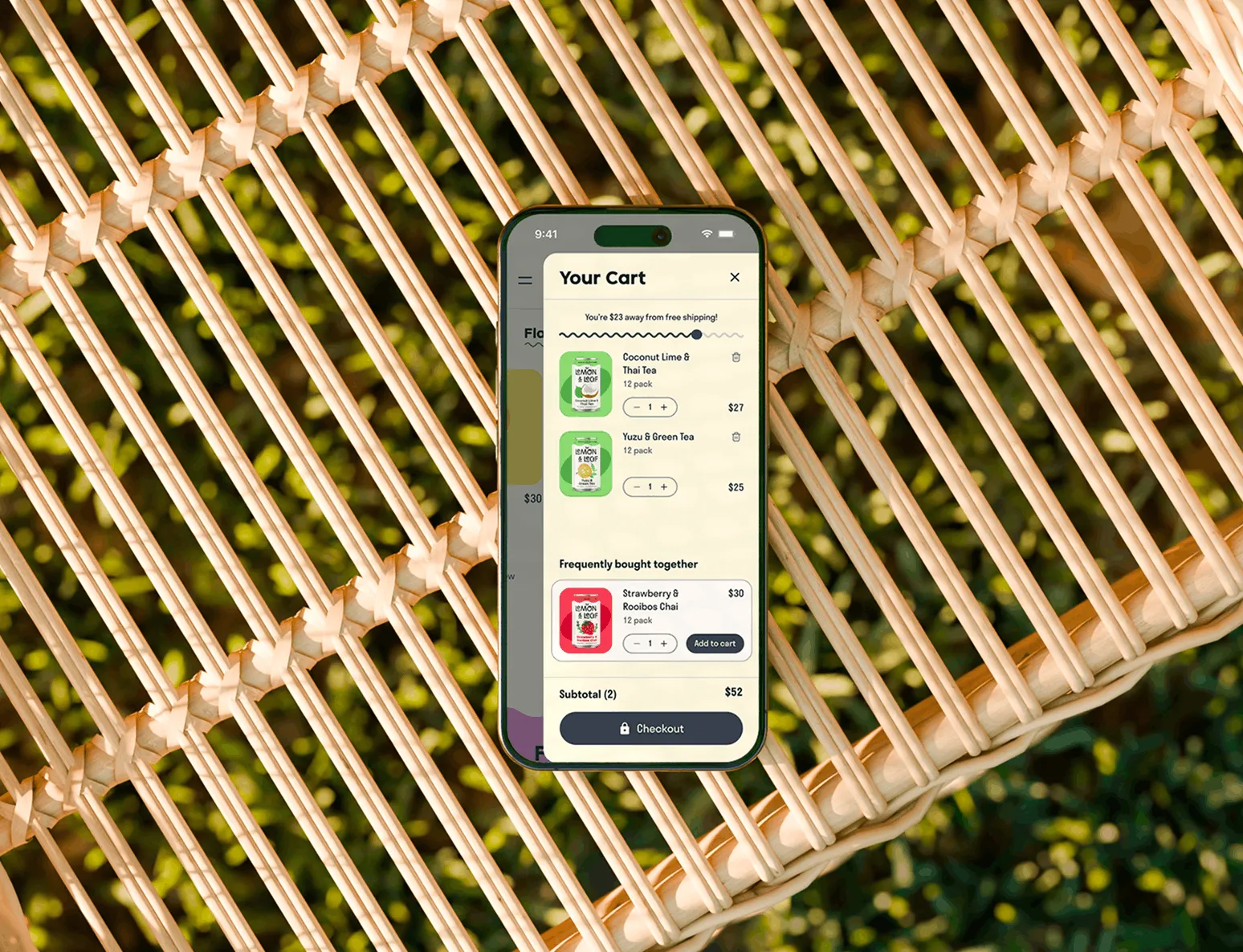 A phone on a woven chair showing the Lemon & Leaf cart panel.