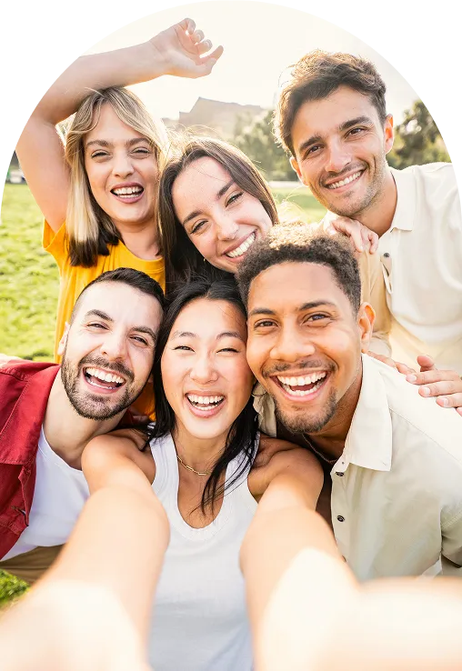 A group of friends taking a selfie together outdoors, laughing.