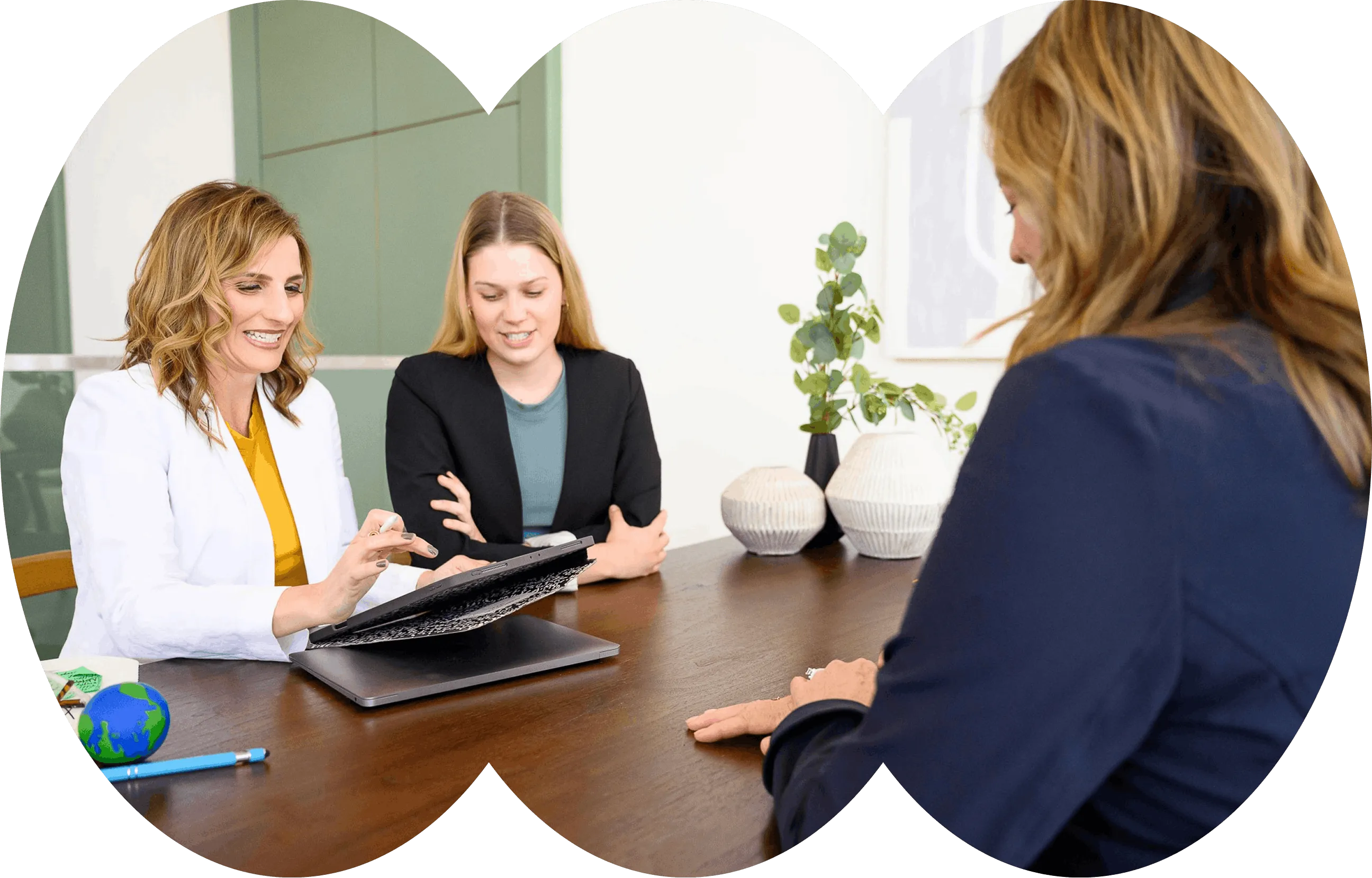 Three women talking around a table in a bright room, shown in arched crops.
