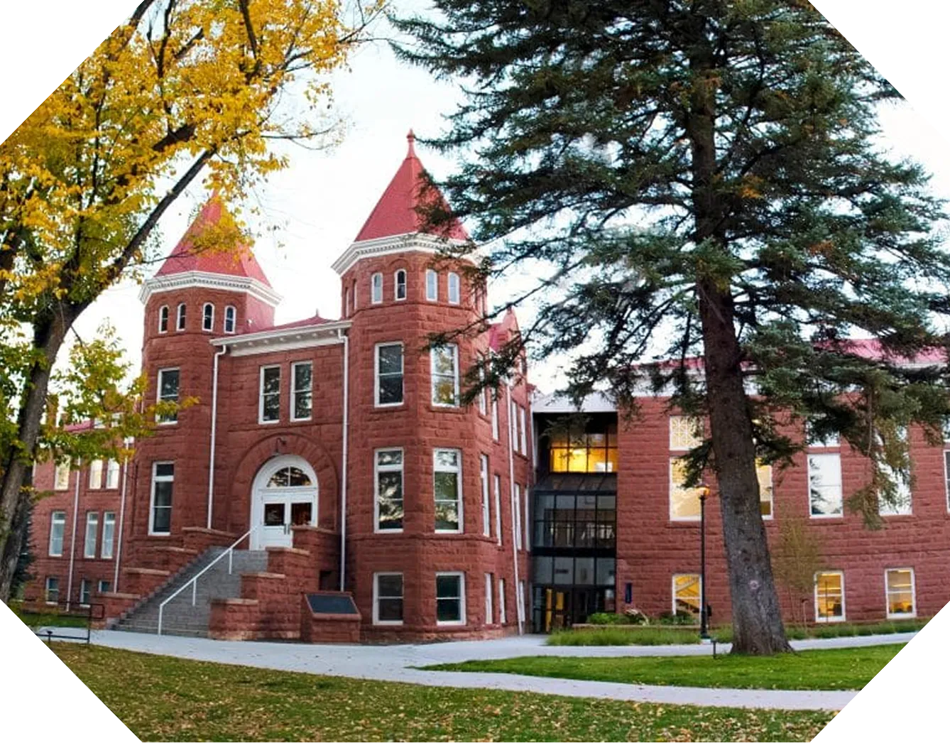 A historic red brick campus building framed by autumn trees.