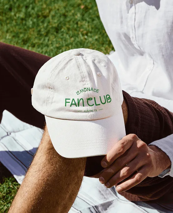 A person wearing a white Lemonade Fan Club baseball cap.