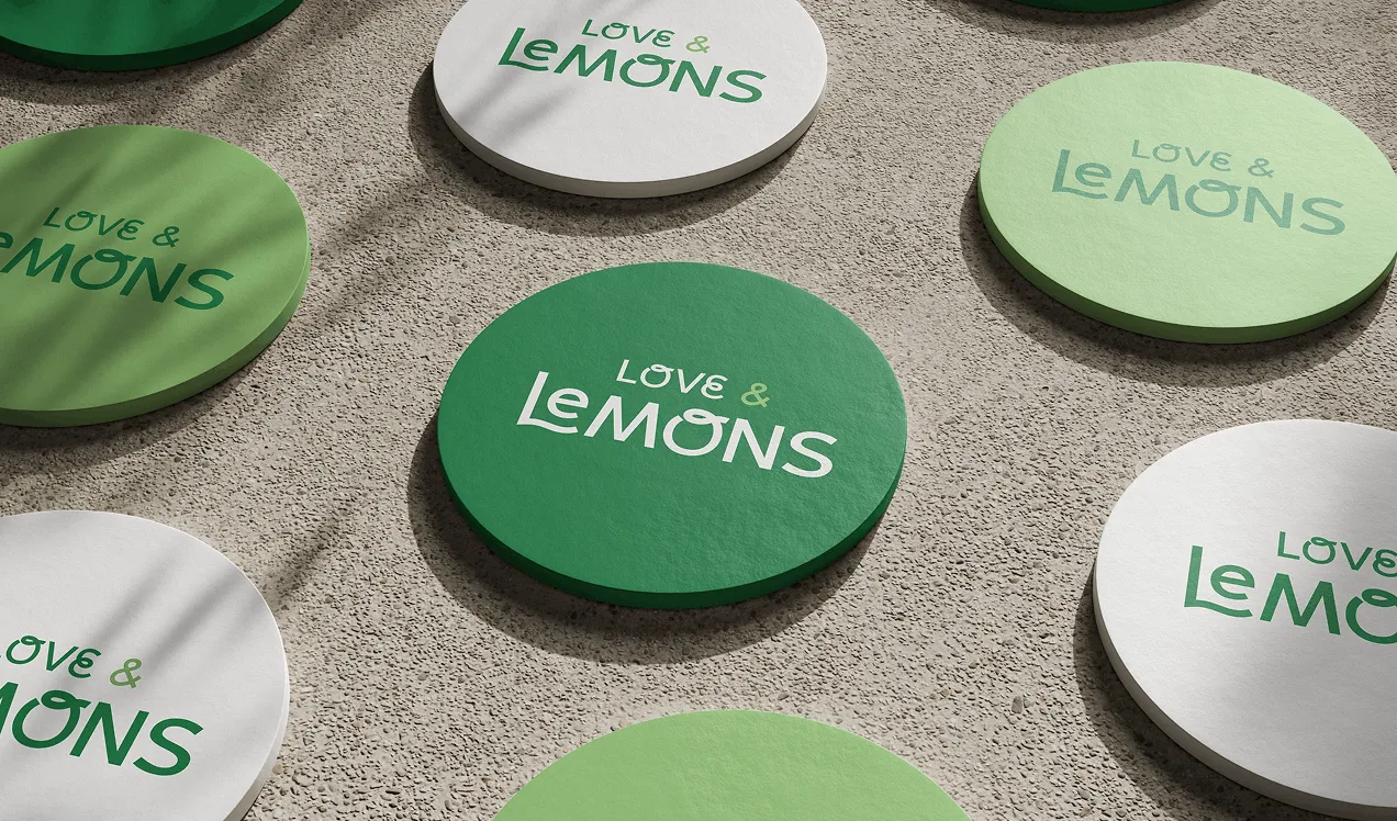 Green and white "Love Lemons" branded coasters scattered on a stone surface.