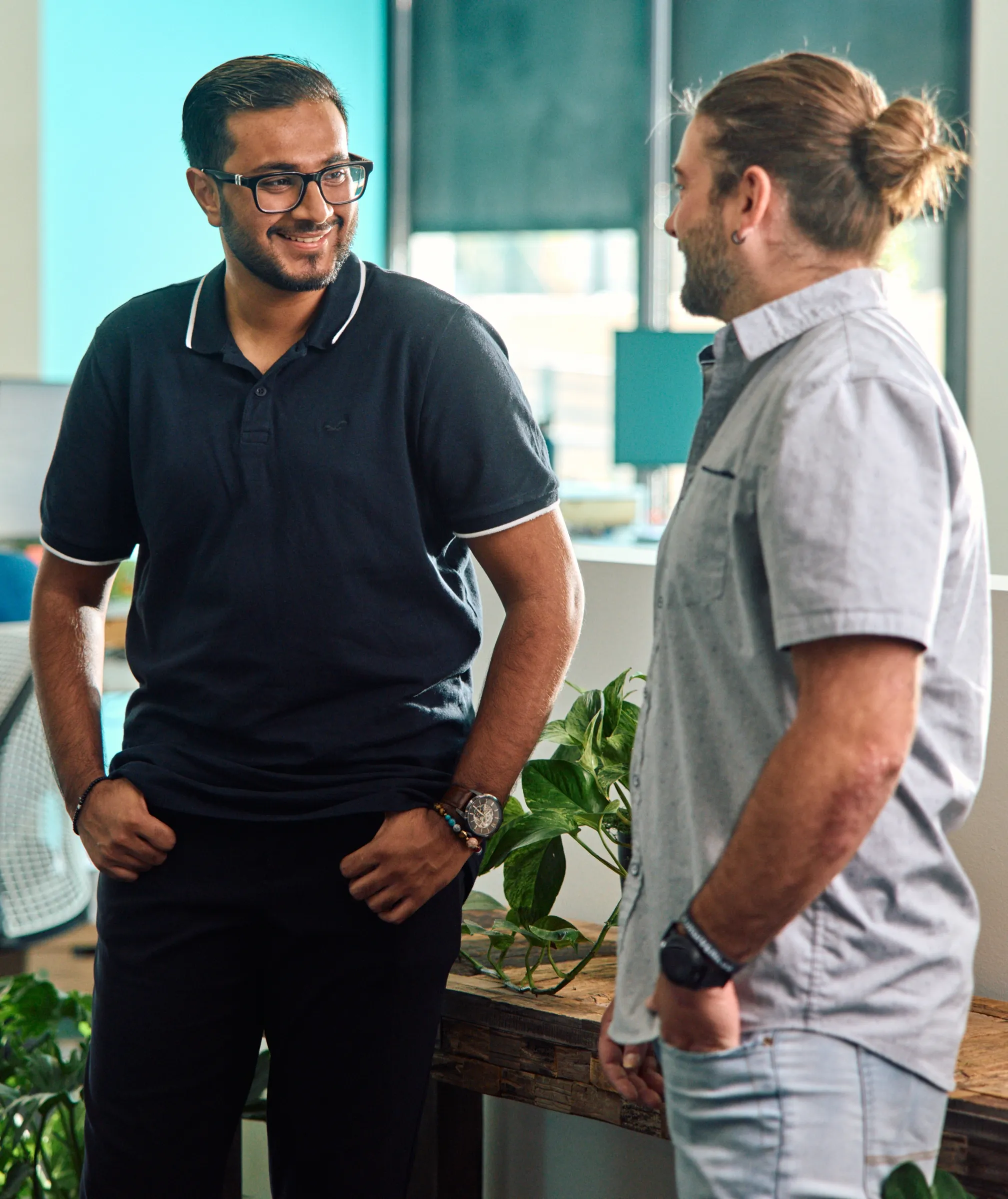 Two colleagues in Paradox polo shirts standing and talking in a bright office.