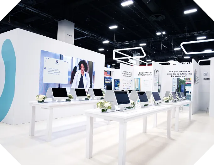 A Paradox exhibition stand with a row of demo monitors along a white counter.