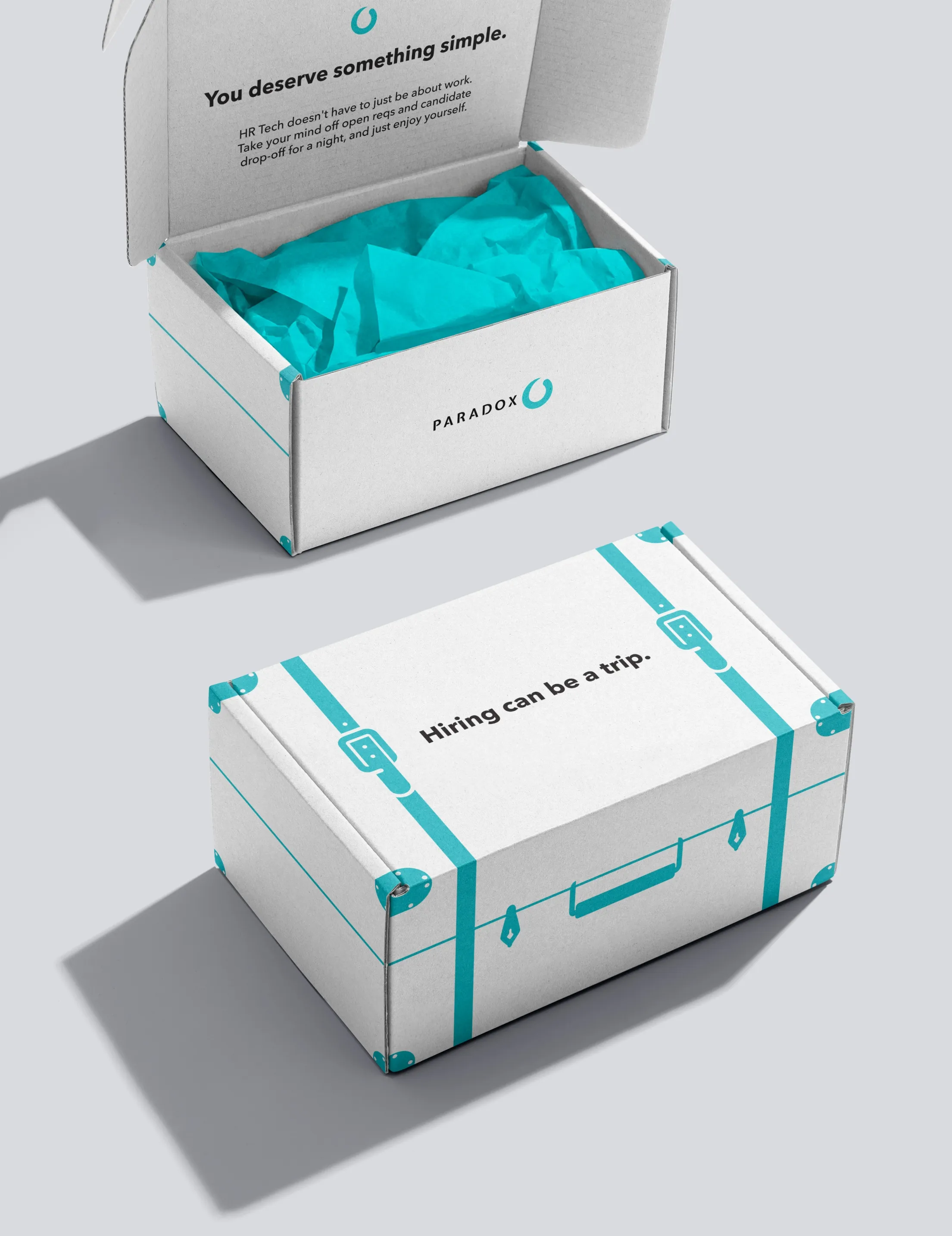 Paradox-branded packaging: an open white box lined with teal tissue beside a suitcase-style box.