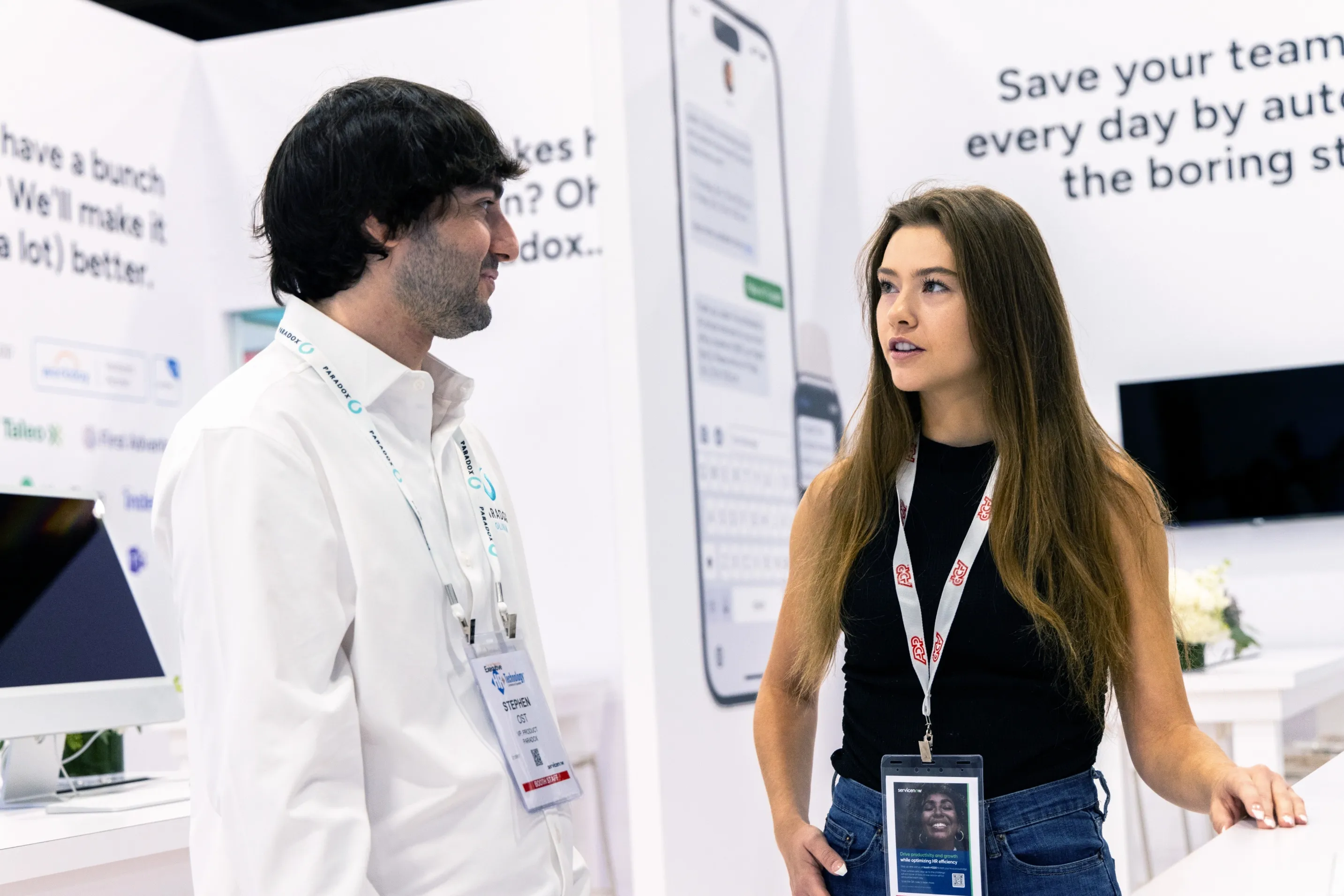 Two conference attendees talking beside a Paradox panel about saving teams from boring work.