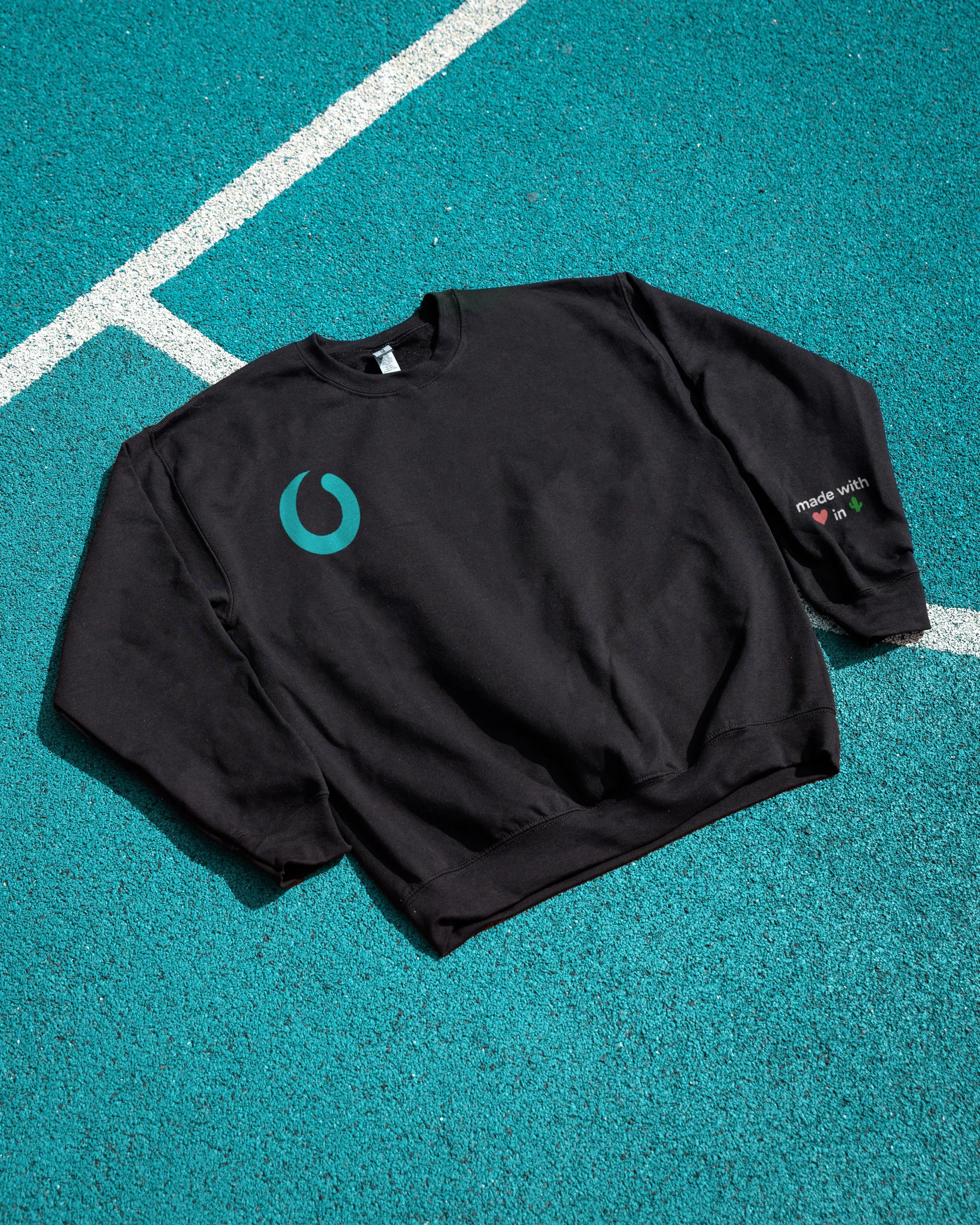 A black Paradox sweatshirt with the brand mark, laid flat on a teal background.