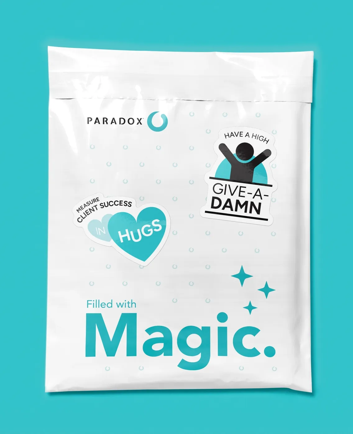 A white Paradox mailer bag printed with "Filled with Magic" and give-a-damn and hugs badges.
