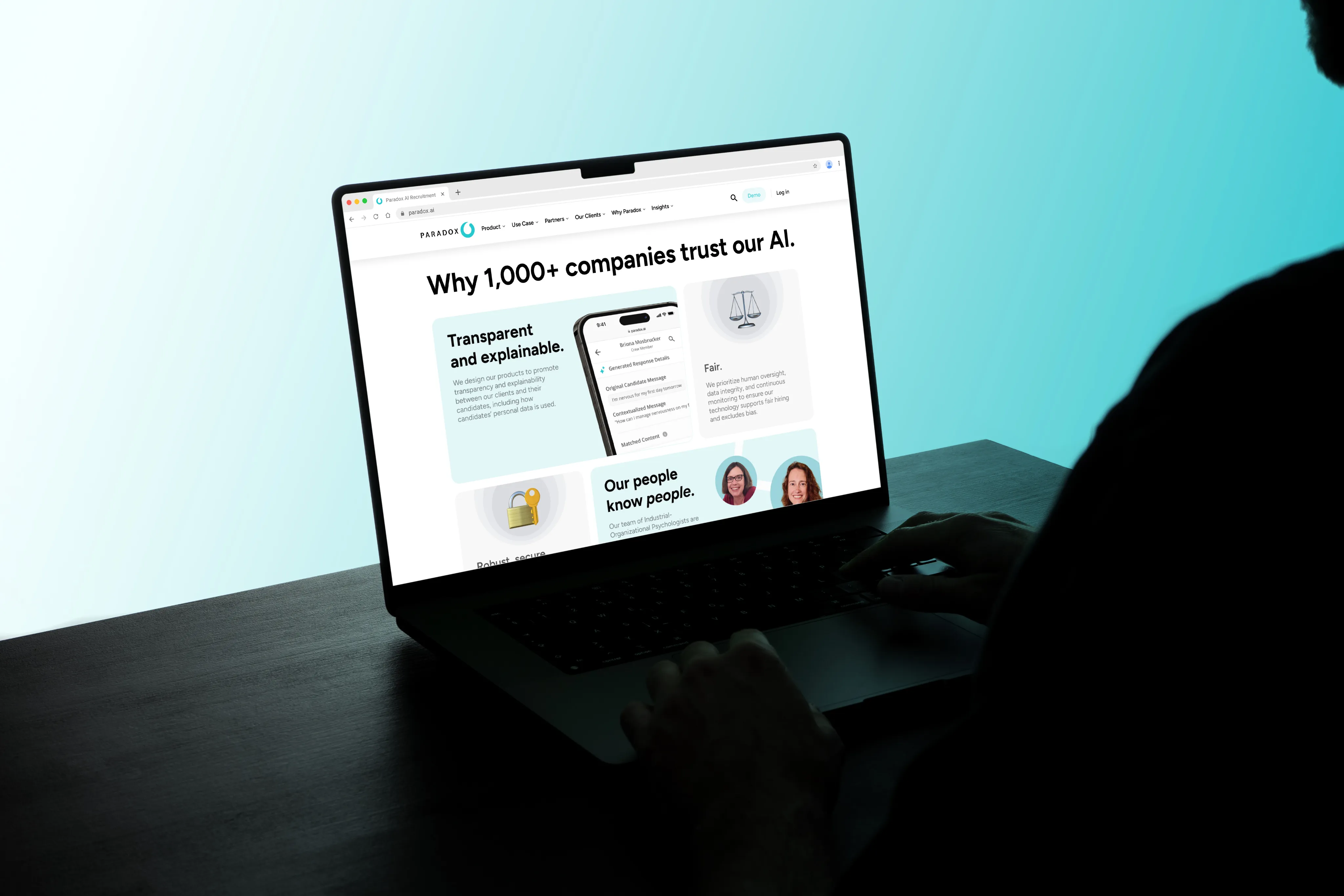 A laptop on a dark desk displaying a Paradox web page headlined "Why 100+ companies trust our AI."