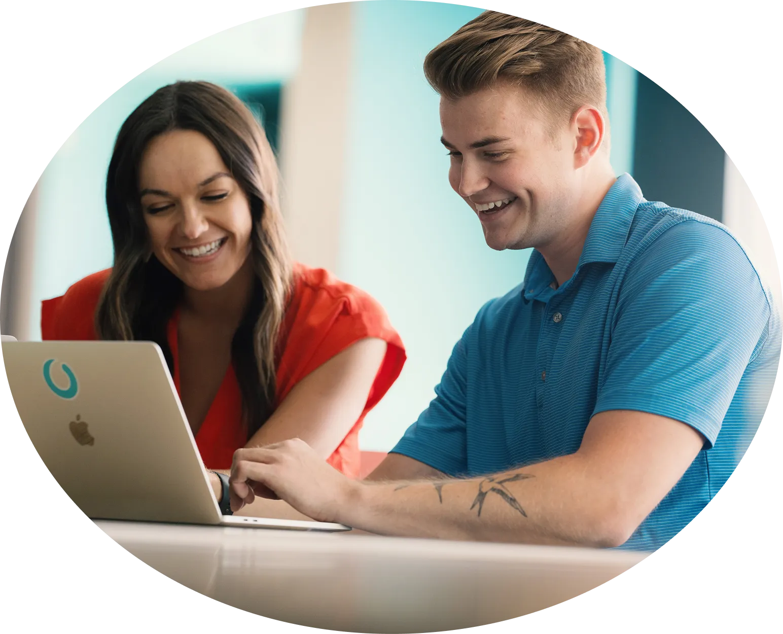 A circular photograph of two colleagues smiling as they look at a laptop together.