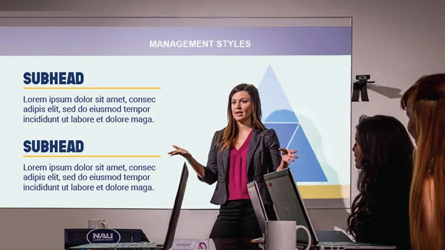 Woman presenting management styles with a slide to colleagues in a meeting room.
