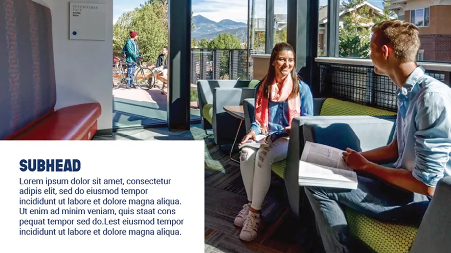 Two students sitting and talking on couches in a bright lounge area with mountain views outside.