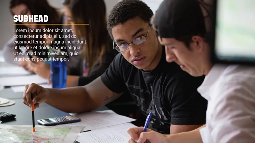 Two people at a table studying documents and a map, one pointing, one taking notes.