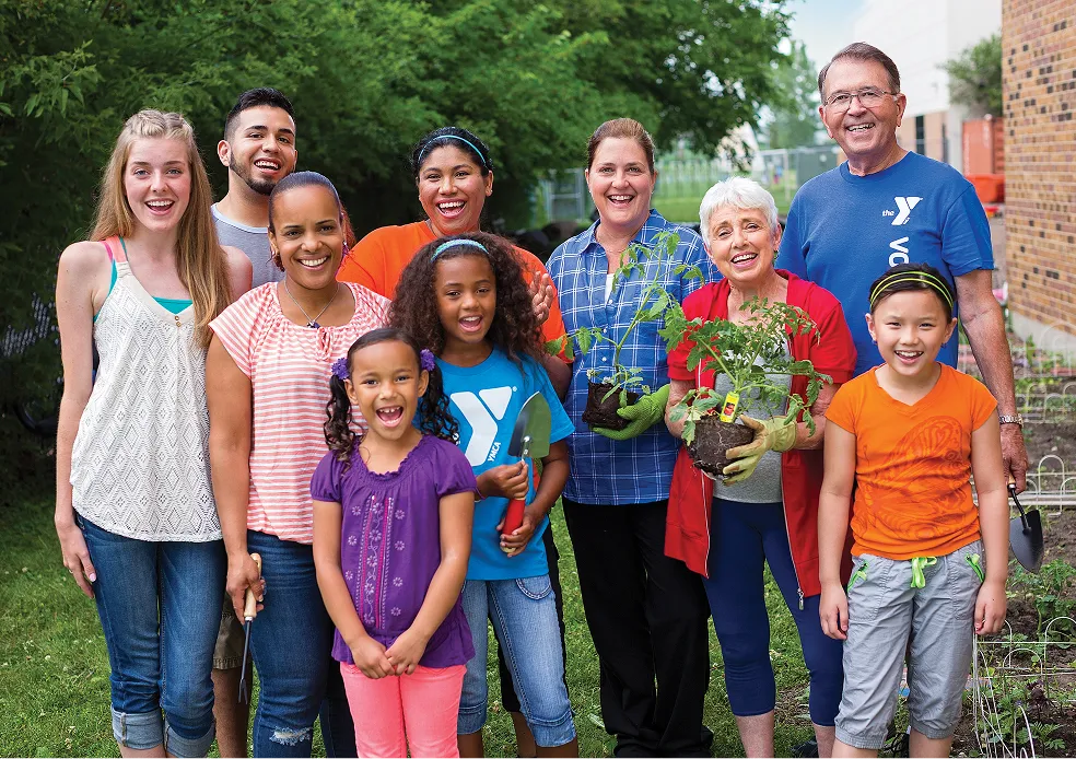 A large multigenerational family posing together outdoors in YMCA t-shirts.