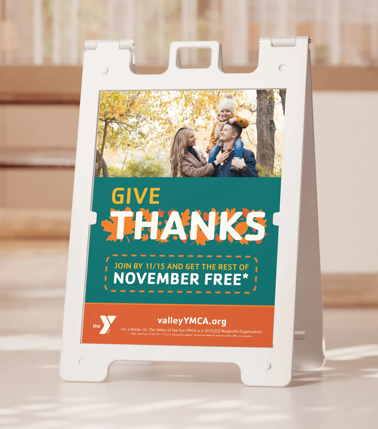 A YMCA "Give Thanks" A-frame pavement sign advertising November free.