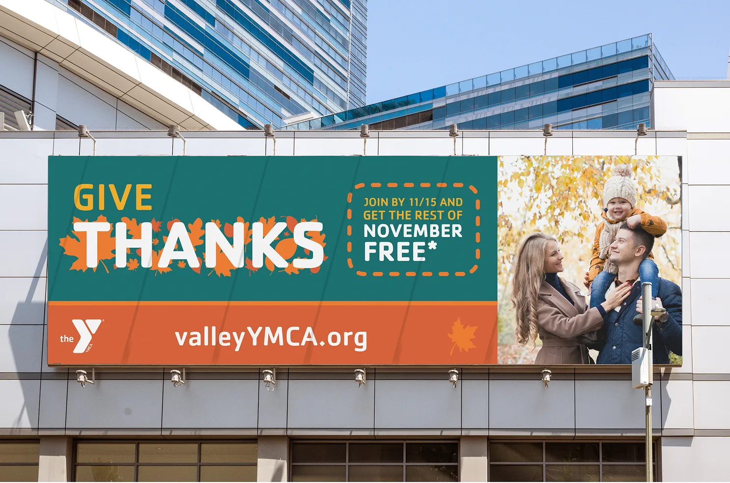 A YMCA "Give Thanks" banner on a building exterior advertising November free.