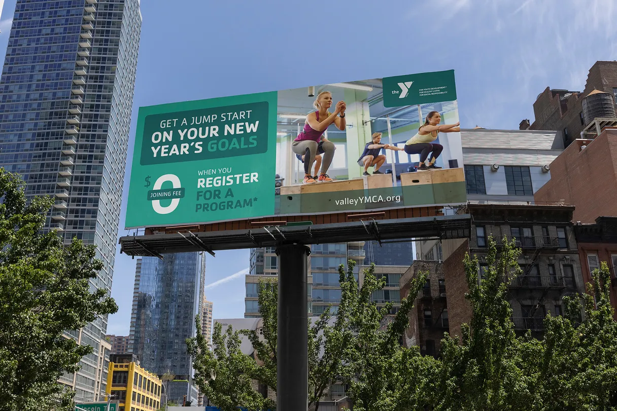 A YMCA New Year's campaign billboard on a city skyline advertising registration.